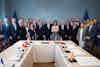 a group of people standing in front of a table with flags